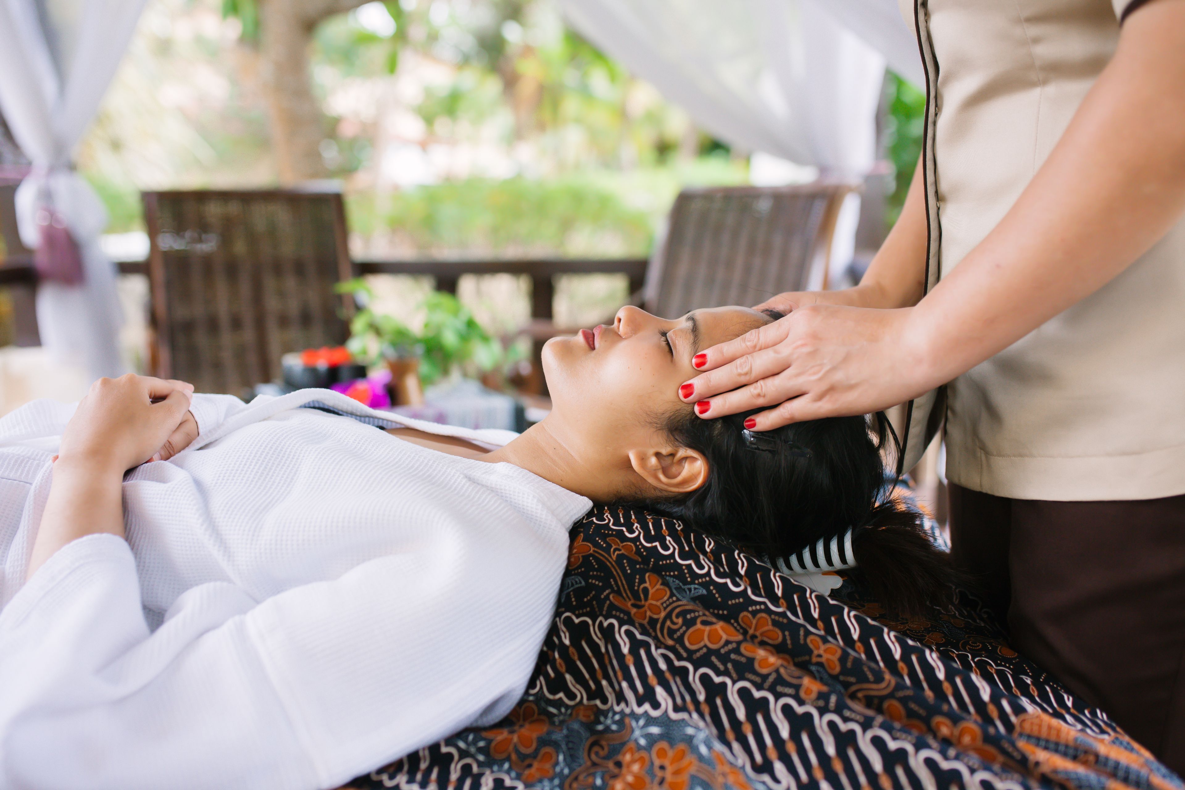Une personne allongée sur une table de massage, recevant un massage de la tête.