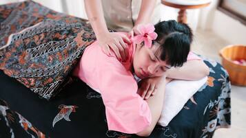 A massage therapy session in progress on a bed with a patterned bedspread.