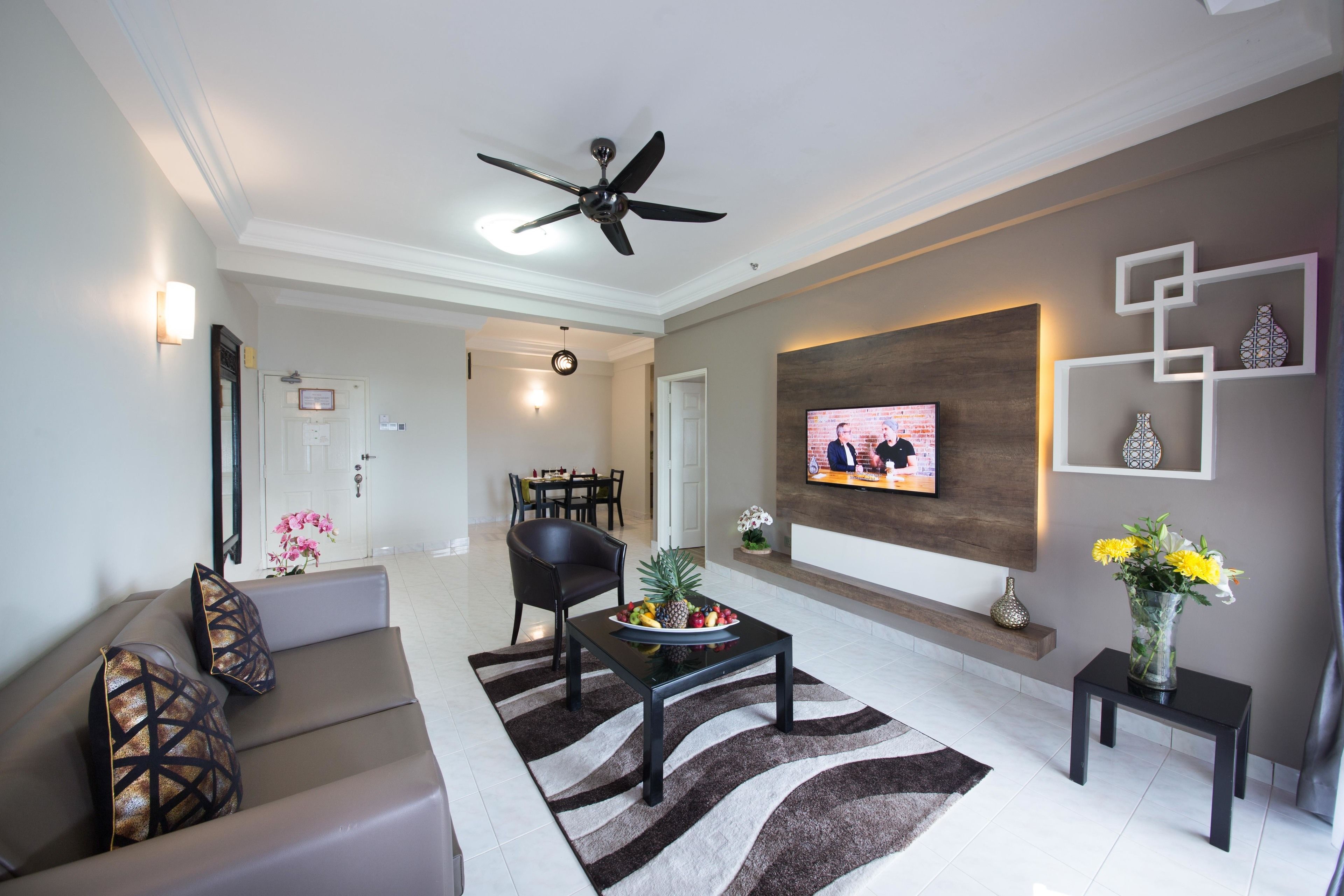 A modern living room with a sofa, coffee table, and a flat-screen TV mounted on the wall.