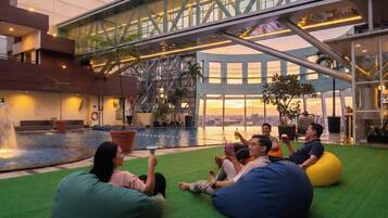 Un área de piscina en la azotea con asientos de césped artificial y vistas al horizonte de la ciudad.