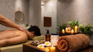 Un entorno de spa con una camilla de masaje, velas, una toalla y productos de spa.