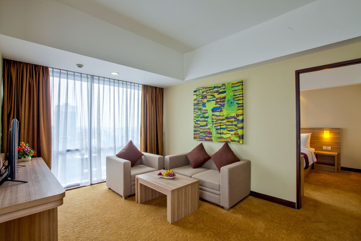 Ein Hotelzimmer mit einer Sitzecke, einem Couchtisch, einem Flachbildfernseher und einem Bild an der Wand.