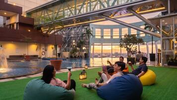 Un grupo de personas descansando en pufs junto a una piscina con vista a la ciudad.