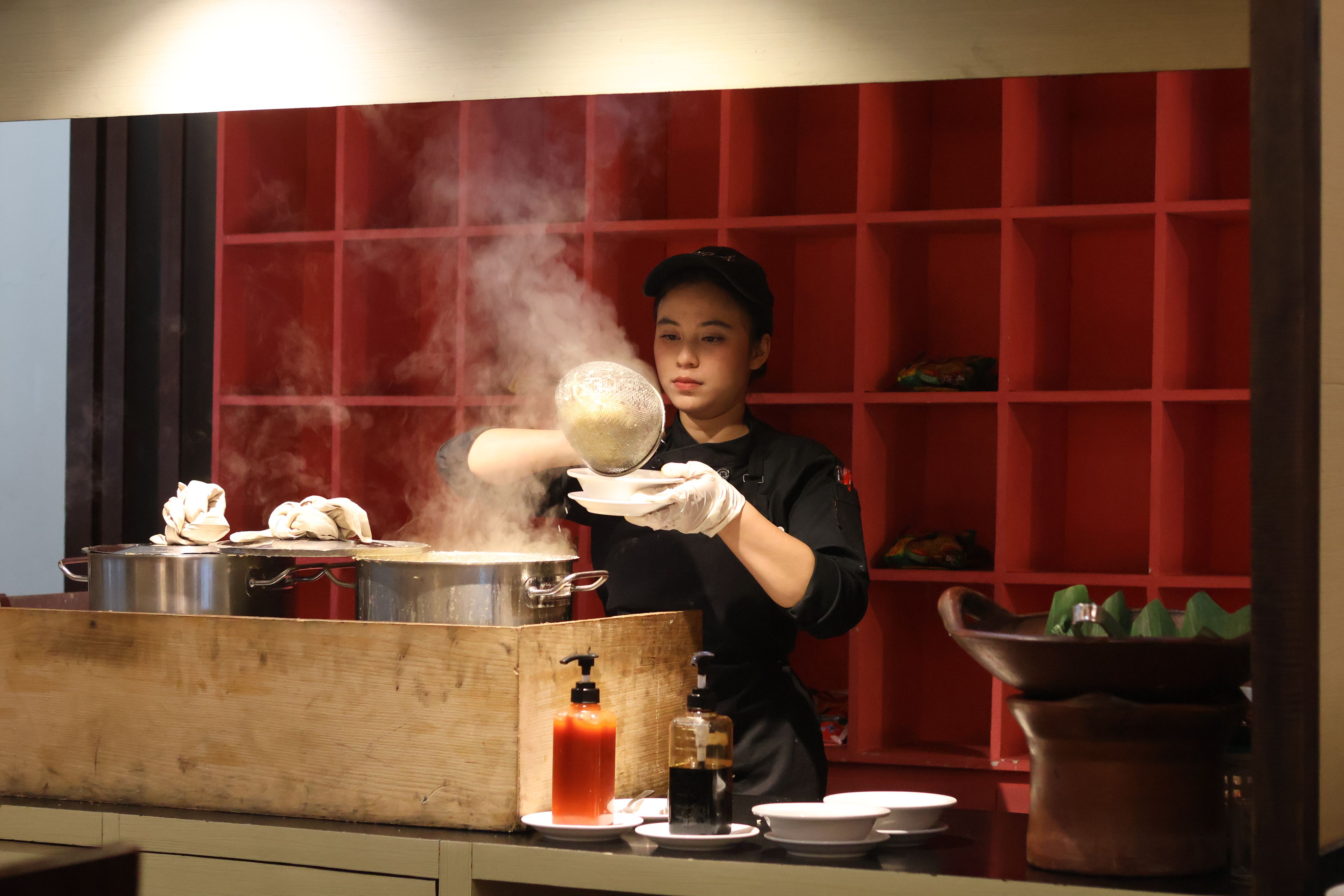A person cooking with steam rising from a pot on a stove.