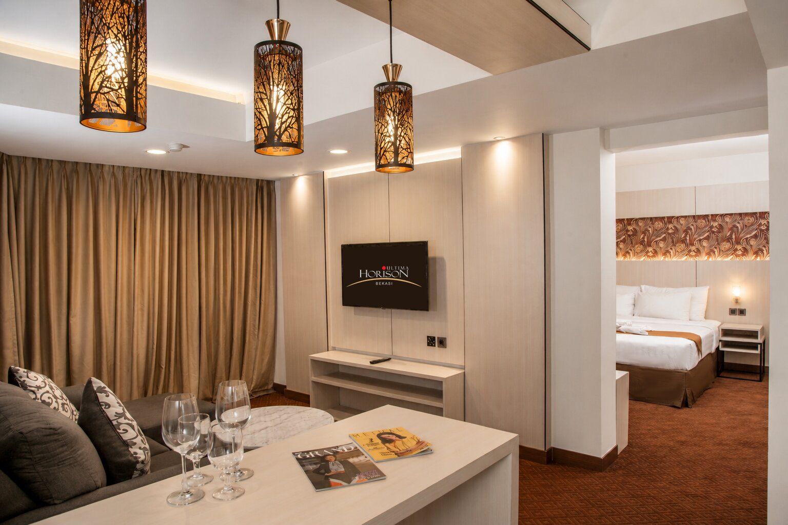 Habitación de hotel con televisión, cama, zona de estar con mesa y sillas, y un panel decorativo en la pared.