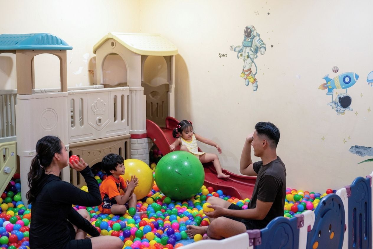 Un'area giochi con uno scivolo, una piscina di palline e un muro decorato a tema spaziale.