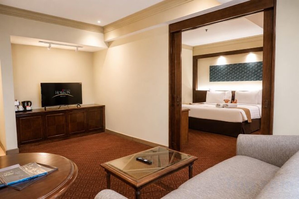 A hotel room with a television, a bed, a sofa, and a coffee table.
