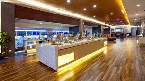 A modern hotel lobby with a central reception desk, wooden flooring, and a large seating area in the background. - Horison Ultima Bekasi (Bekasi)
