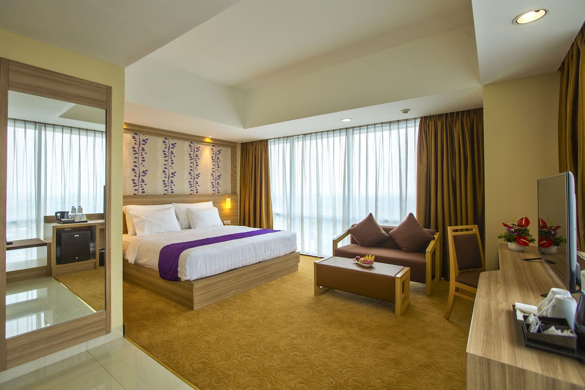 Ein Hotelzimmer mit einem großen Bett, einer Couch, einem Couchtisch, einem Schreibtisch und einem Fernseher.