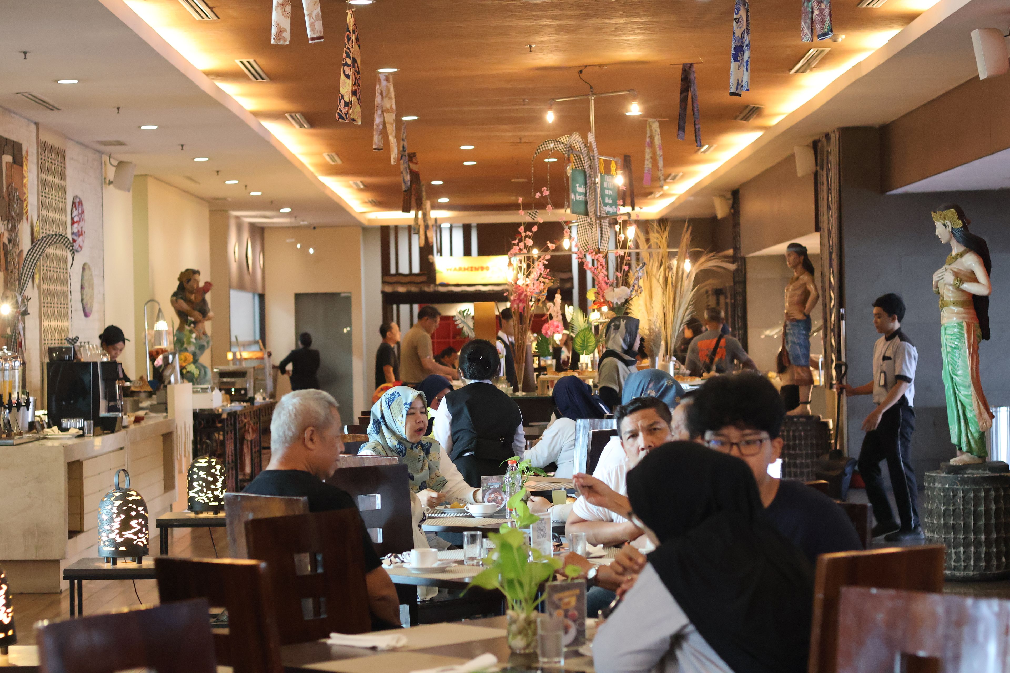 A restaurant interior with multiple dining tables, chairs, and hanging decorations.
