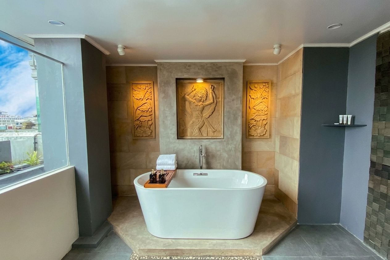 A modern bathroom with a freestanding bathtub, decorative wall panels, and a view through a window.