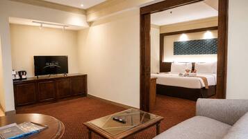 Una habitación de hotel con cama, televisión, escritorio y sofá.