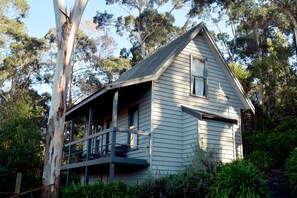 A single-story house with a balcony, surrounded by dense greenery and trees. - Great Ocean Road Cottages (Lorne)