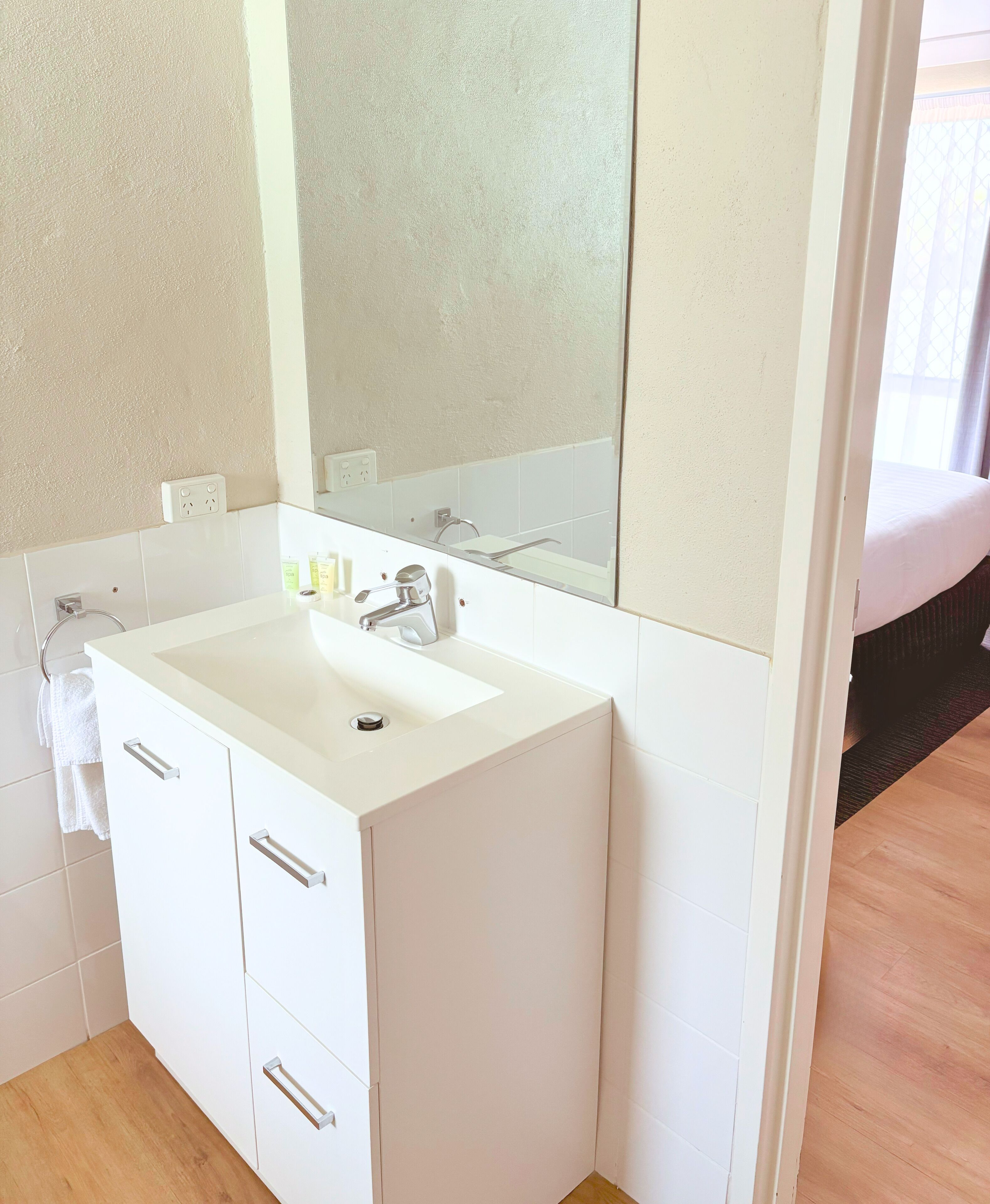 Un baño moderno con lavamanos, espejo y mueble blancos.
