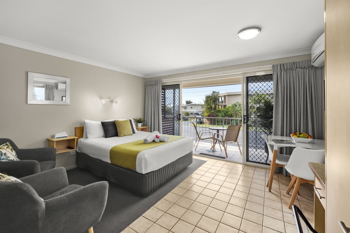 Ein Hotelzimmer mit Bett, Schreibtisch, Stuhl, Sofa und einem Balkon mit Blick.