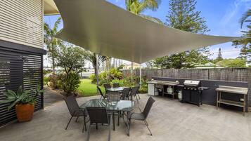 Enjoy dining and socializing in this outdoor space with a glass-top table and barbecue grill.
