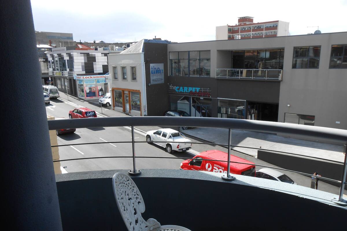 Une vue d’une rue bordée de divers commerces, notamment un magasin de tapis et une serrurerie.