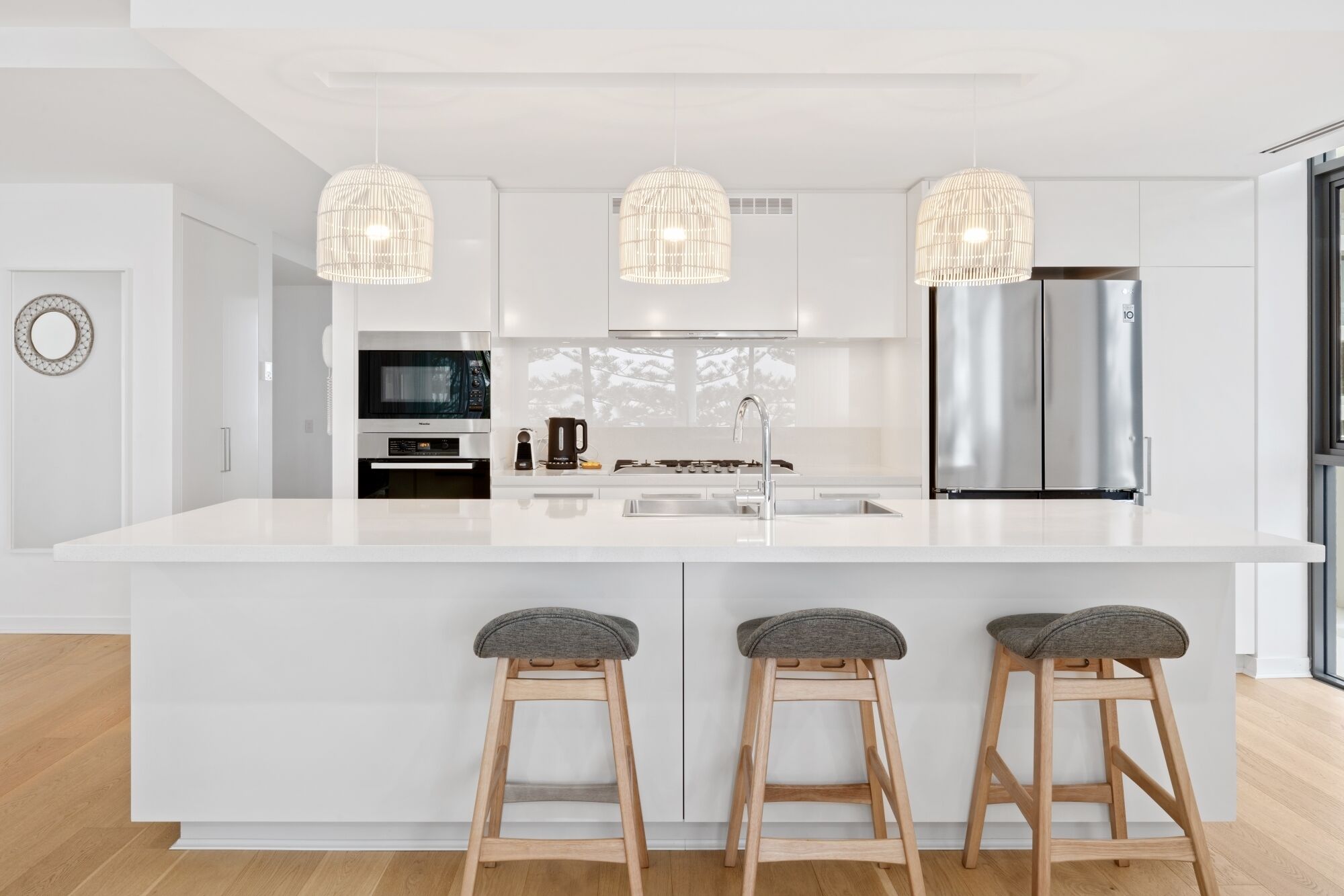 A modern kitchen with a large island, stainless steel appliances, and pendant lighting.