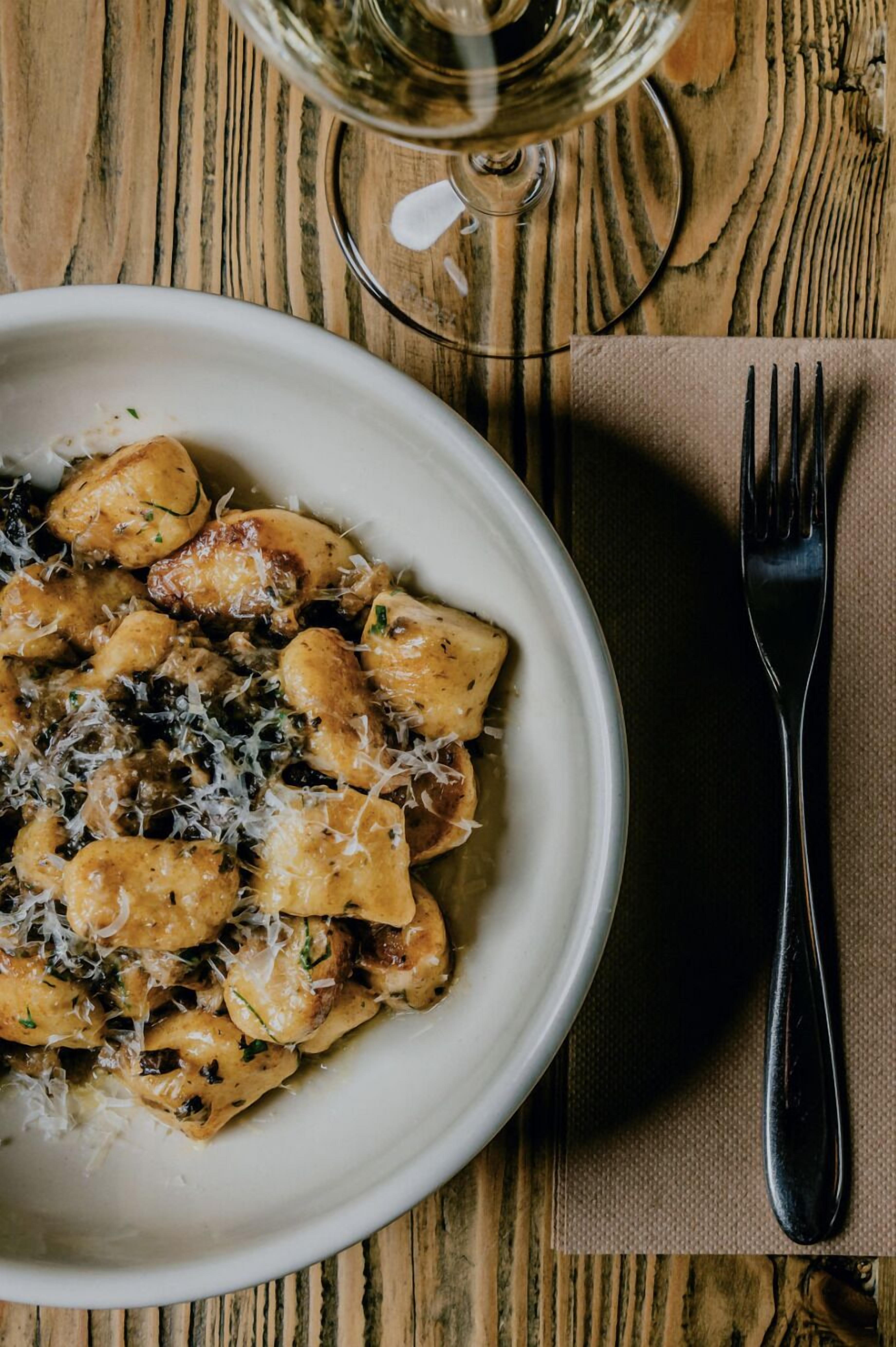 Un plato de pasta con queso sobre una mesa de madera.
