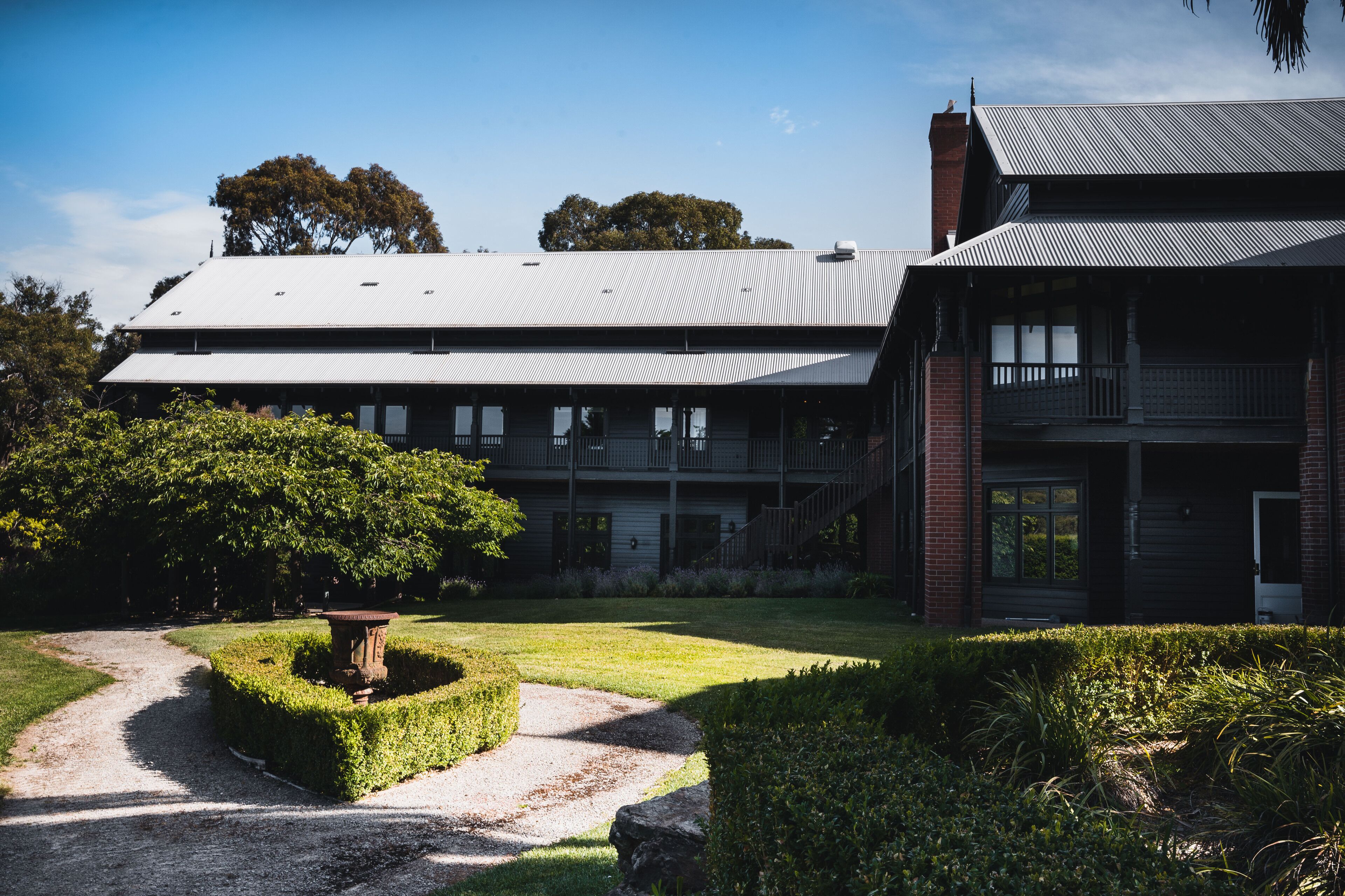 A large two-story building with a metal roof, a brick chimney, and a balcony.