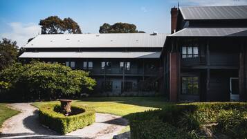 A large two-story building with a metal roof, a brick chimney, and a balcony.