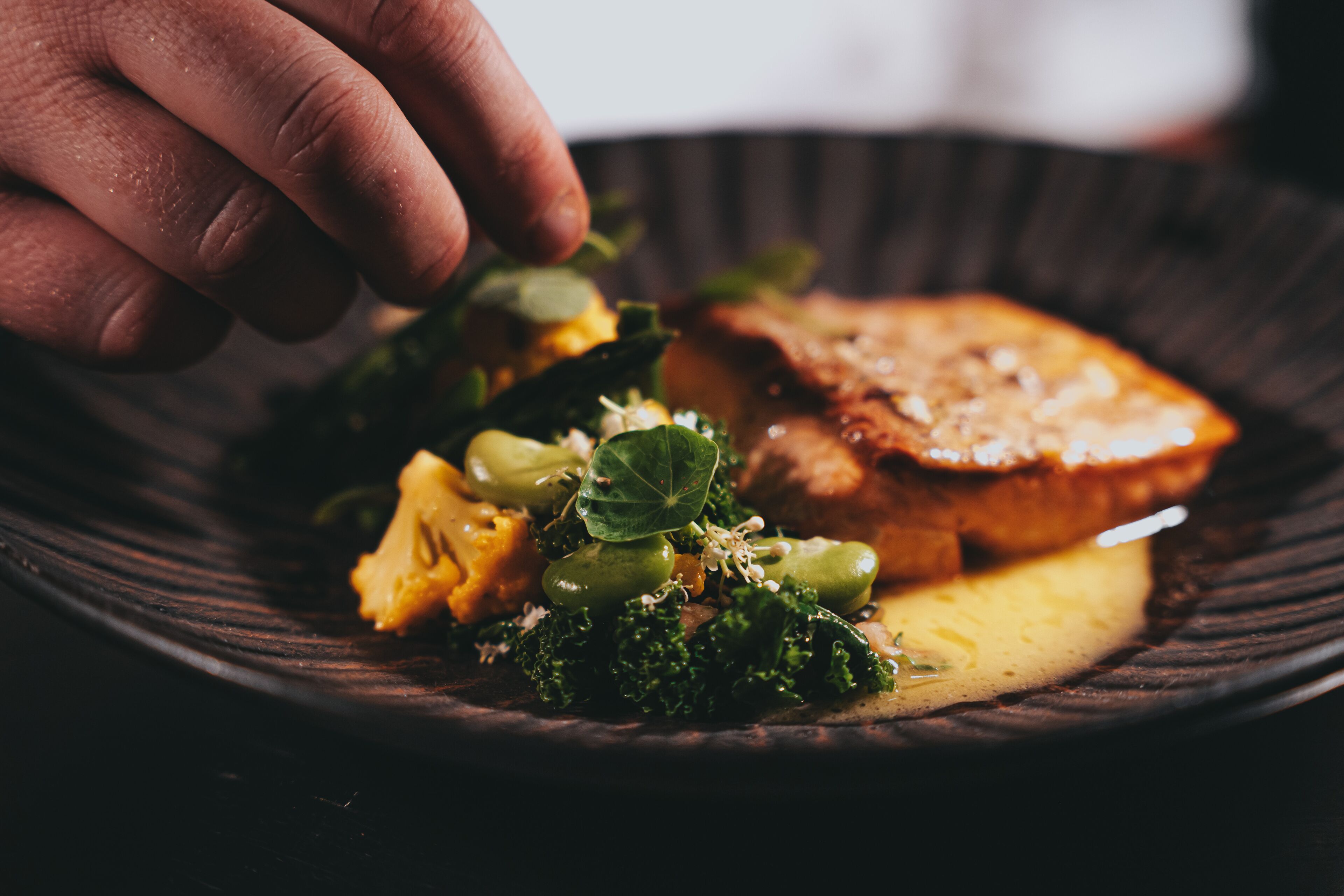 Une assiette avec une tranche de pain grillé, des brocolis et une main qui tend la main pour les prendre.