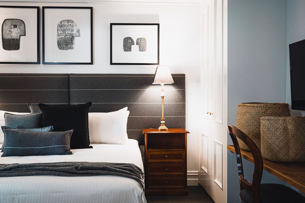 A neatly arranged bedroom with a bed, bedside tables, and a chair.