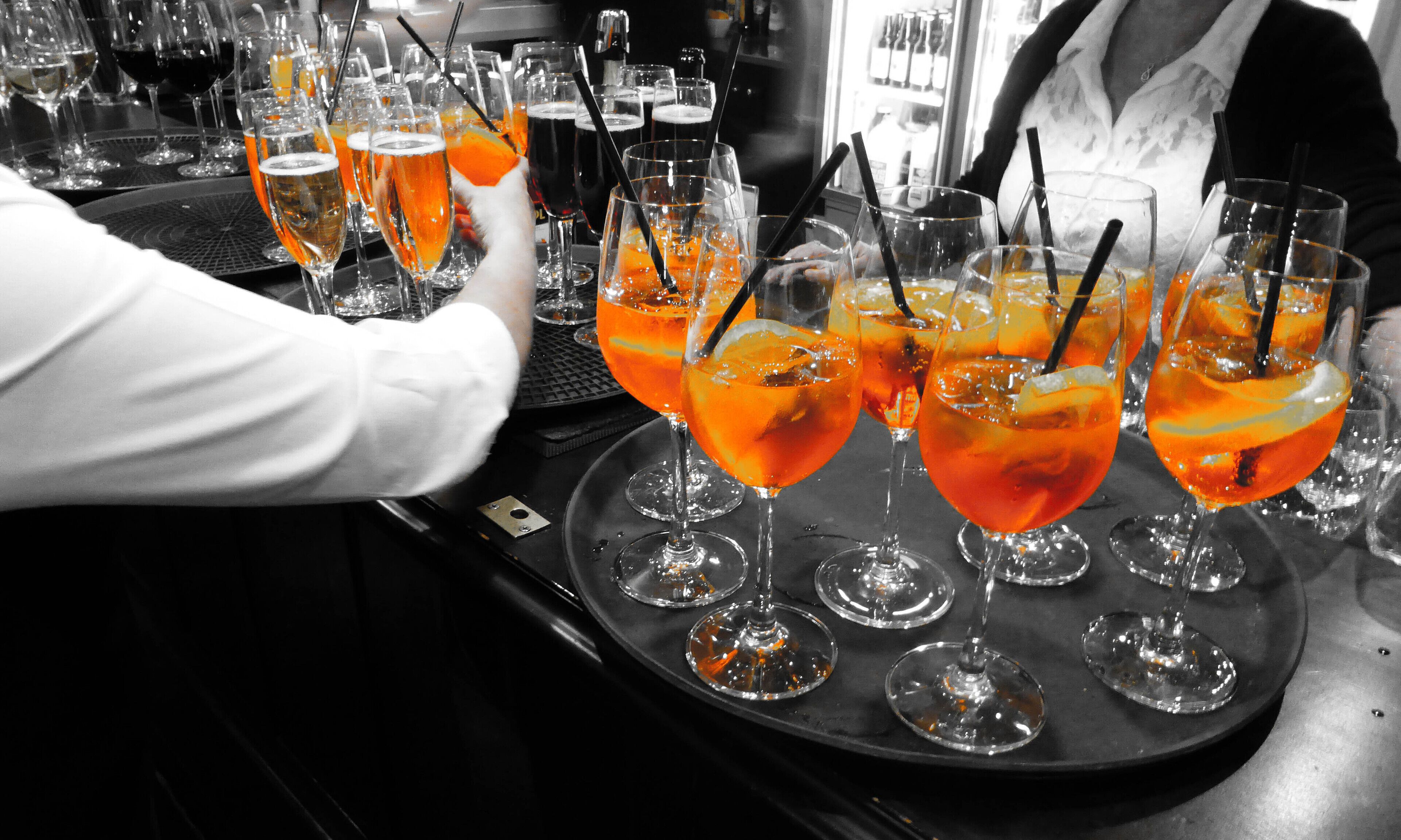 Un bar avec plusieurs verres de cocktails à l’orange, dont certains sont servis avec des pailles, disposés sur un plateau.