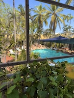 A pool area with palm trees and a view of a building in the background.