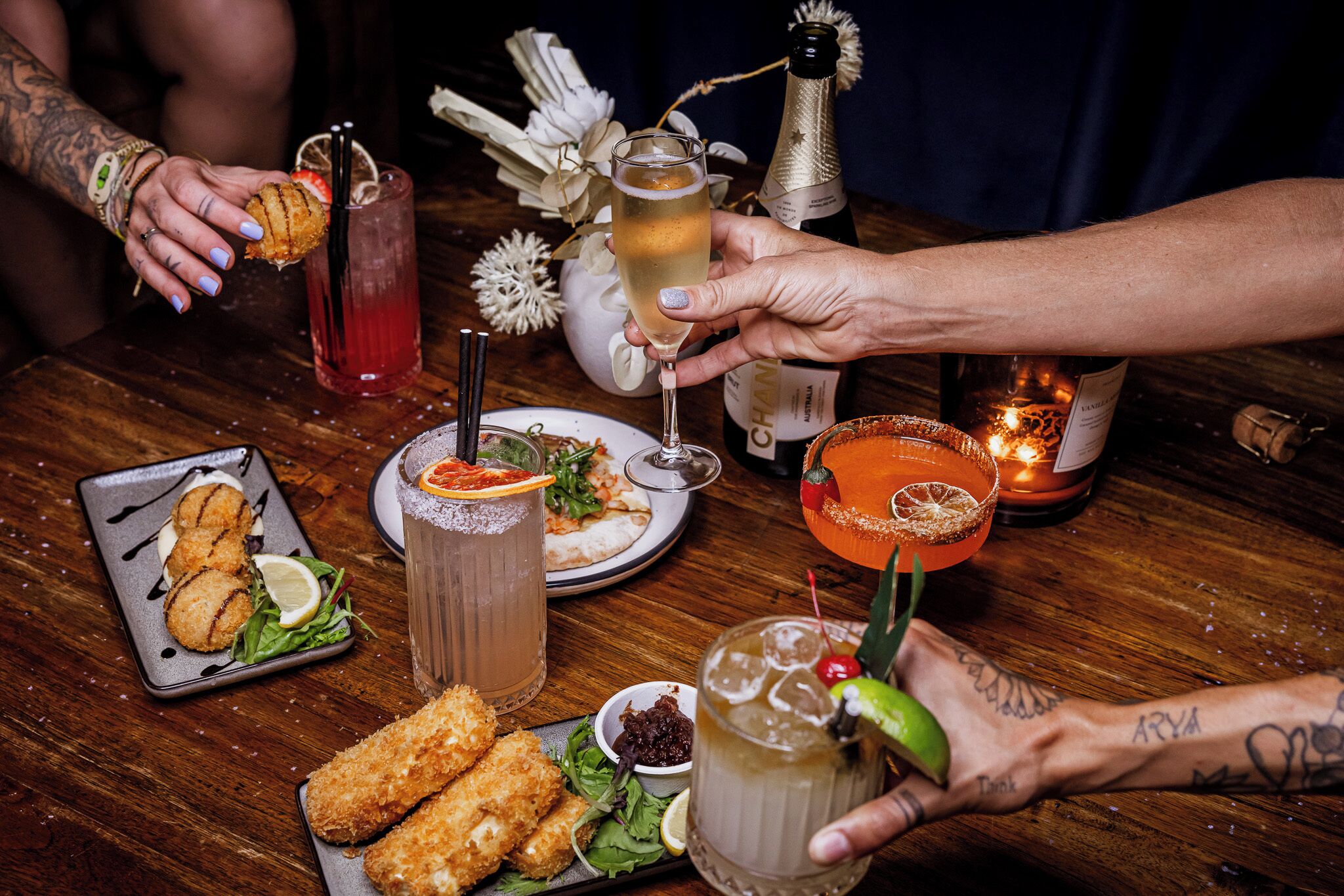 Une table en bois sur laquelle sont disposés divers aliments, des boissons et une bougie.