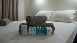 Una cama bien hecha con toallas enrolladas y artículos de spa.