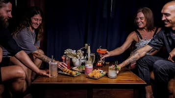 A group of people seated around a wooden table with various food items and drinks.