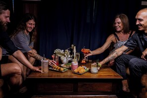 Un grupo de personas sentadas alrededor de una mesa de madera con diversos alimentos y bebidas.