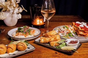 Una mesa con diferentes platos, una copa de vino y una vela.
