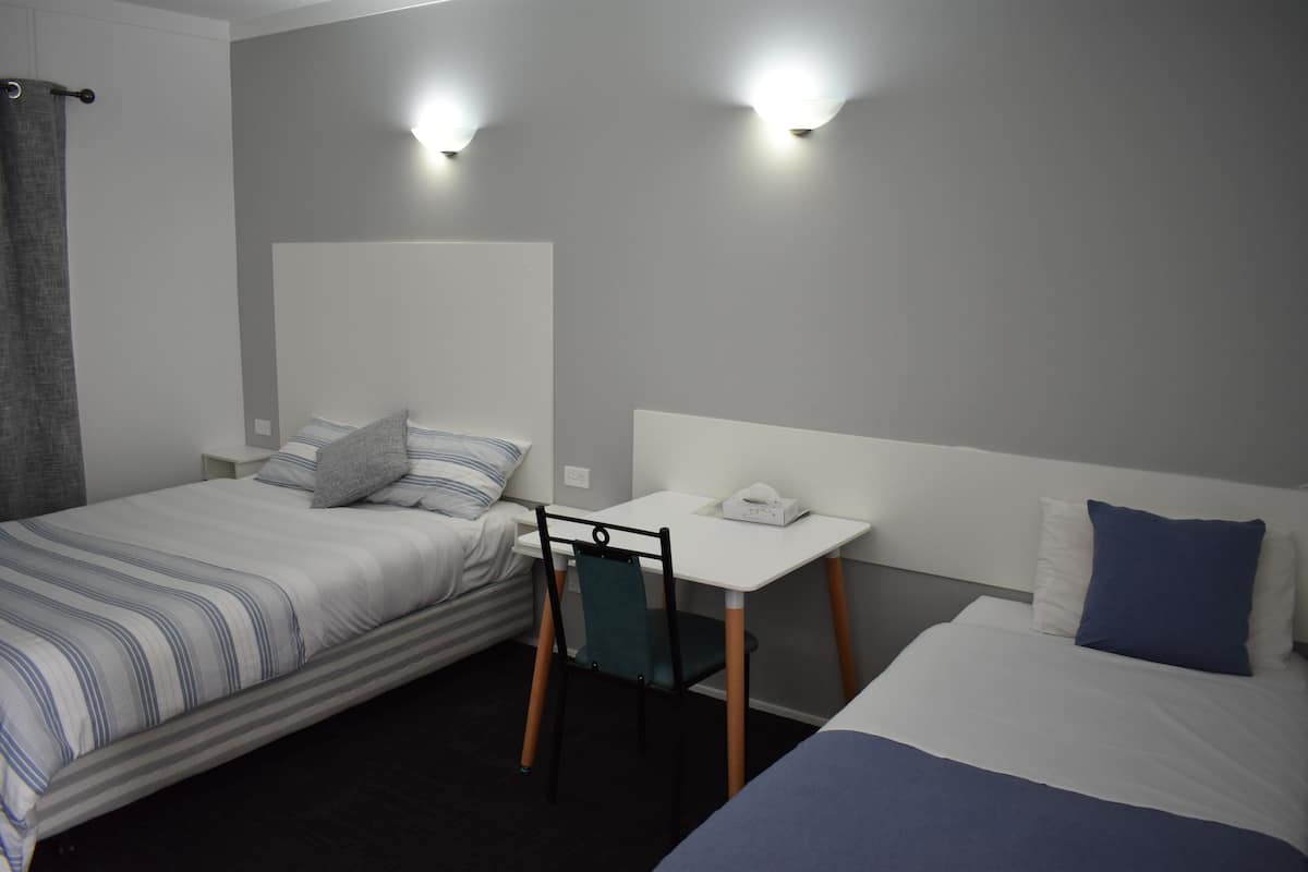 Une chambre d’hôtel avec deux lits, un bureau et une chaise.