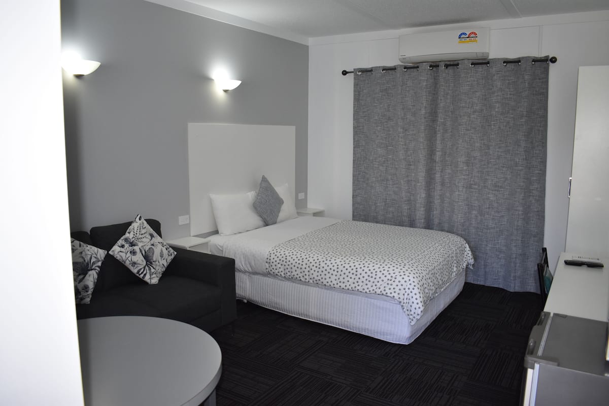 Une chambre d’hôtel avec un lit, un canapé, une petite table et un bureau.