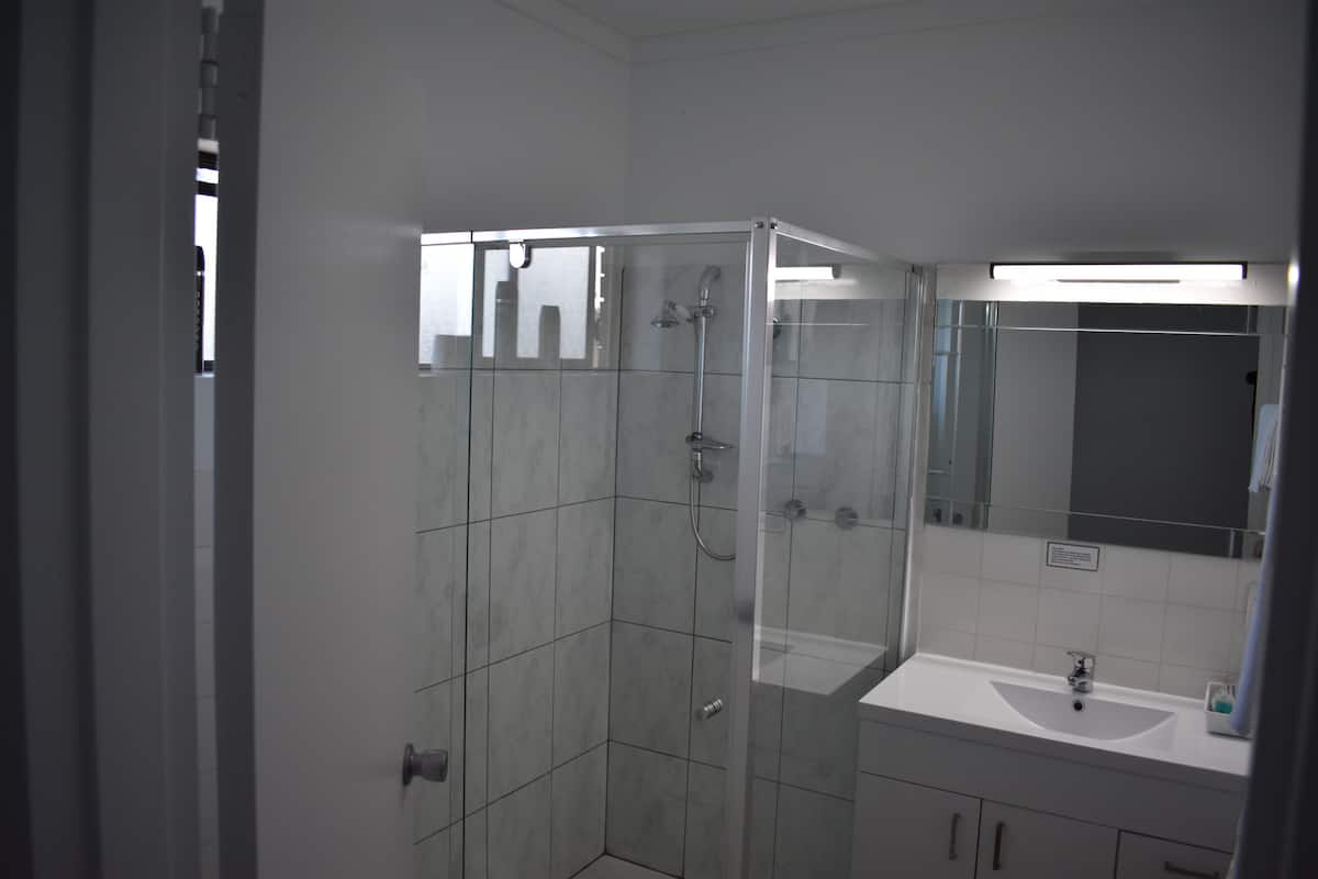 Une salle de bain moderne avec une douche à parois de verre, un lavabo blanc et un grand miroir.