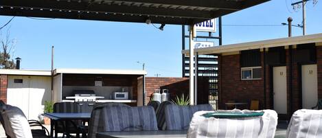Un motel con asientos al aire libre, una parrilla de barbacoa y un edificio de ladrillo.