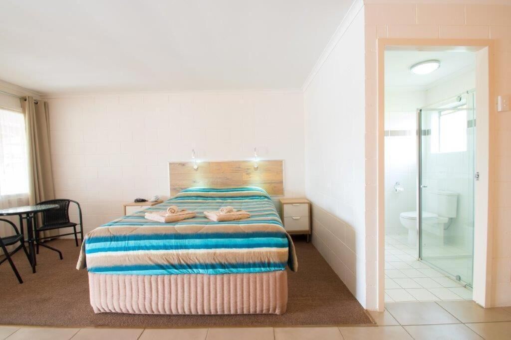 Hotelkamer met een bed, een tafeltje, een stoel en een badkamer zichtbaar door een glazen deur.