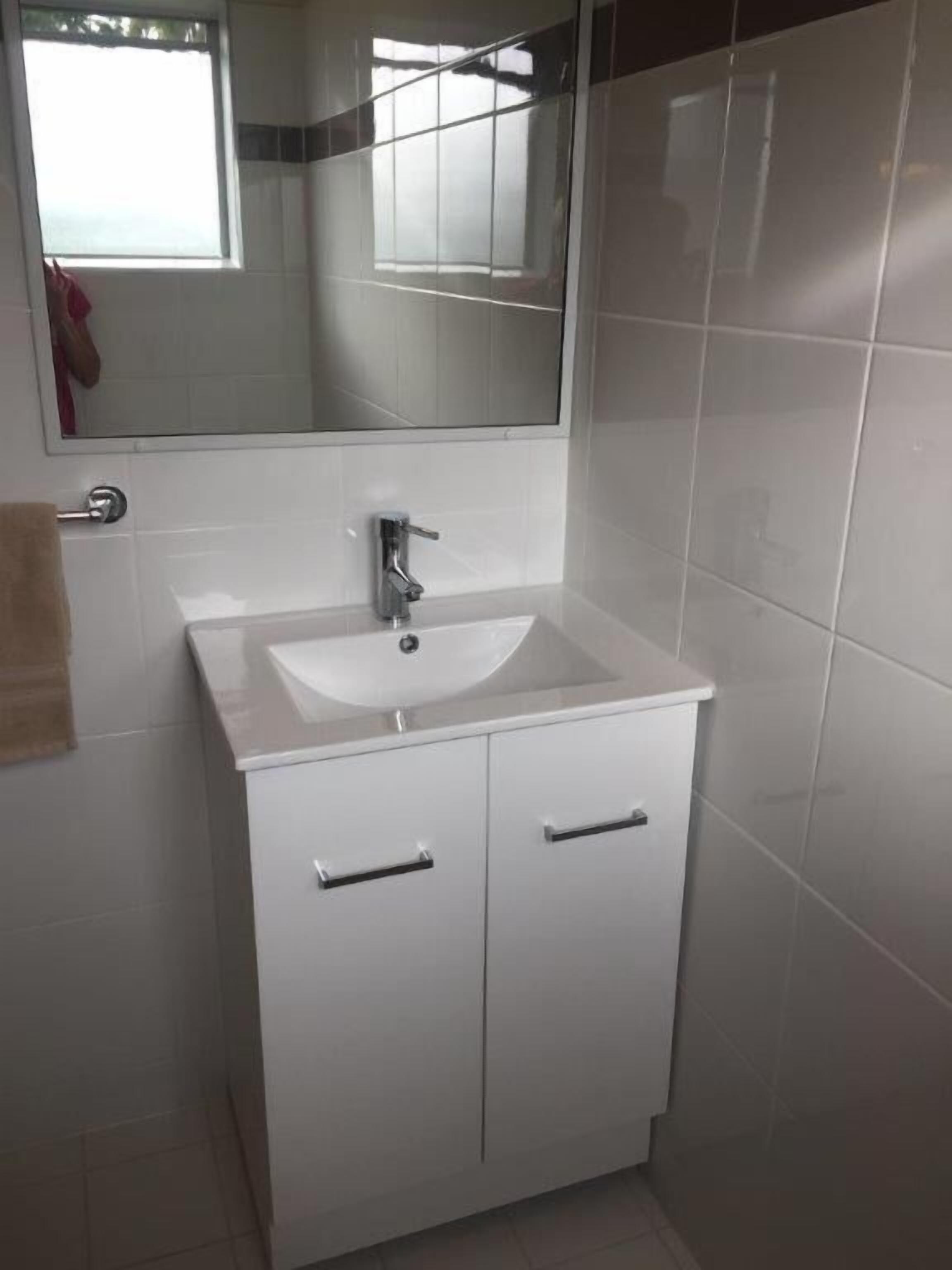 A bathroom with a white sink, a mirror above it, and two cabinets below.
