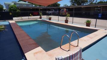 Una piscina al aire libre, sillones reclinables de piscina