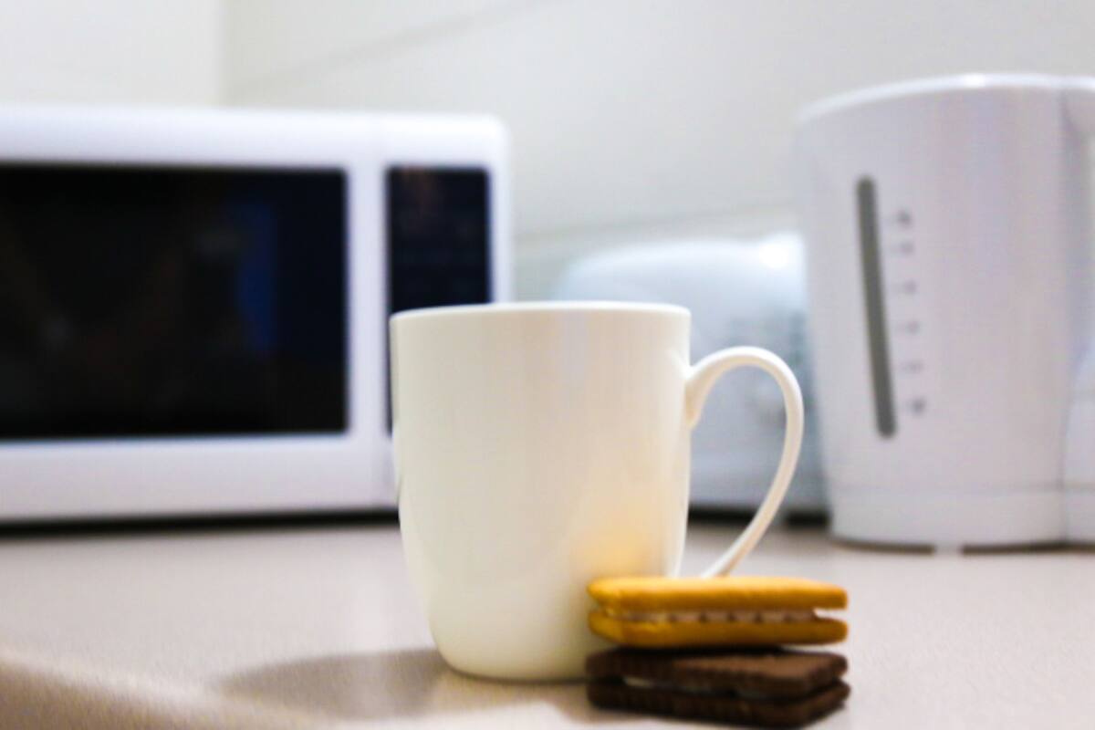 Une tasse blanche et une machine à café blanche sont posées sur un plan de travail de cuisine.