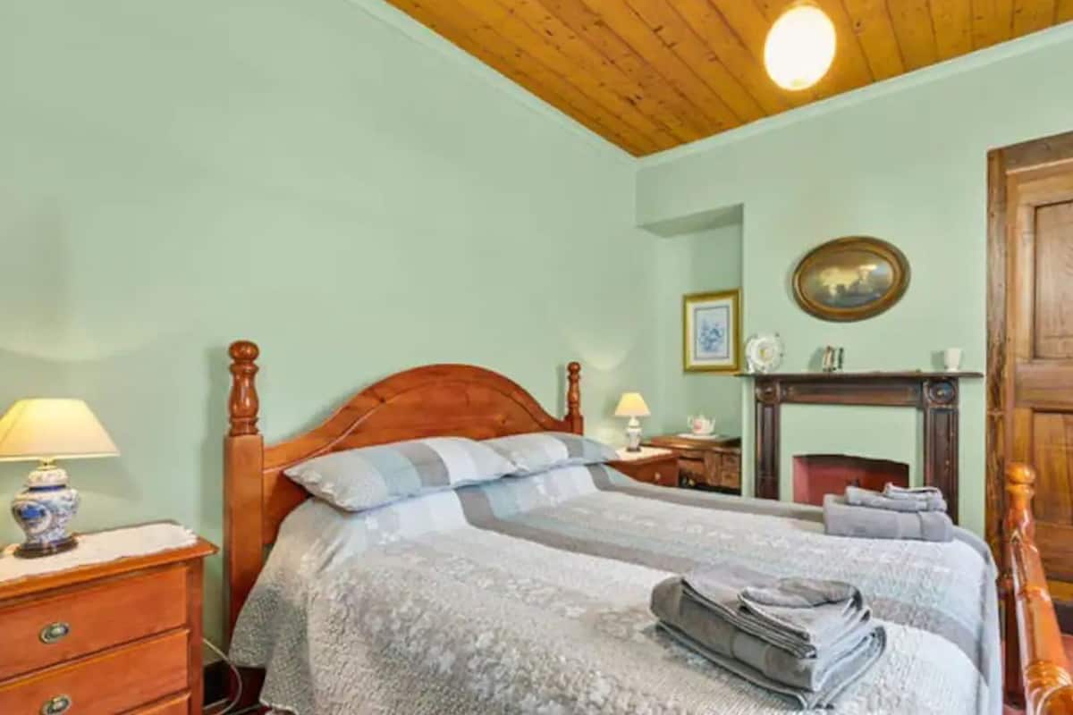 A bedroom with a wooden bed, a nightstand, a dresser, a mirror, and a wardrobe.
