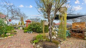 A garden patio with a brick pathway, a tree with hanging baskets, and a brick barbecue area. - Sorell Barracks (Sorell)