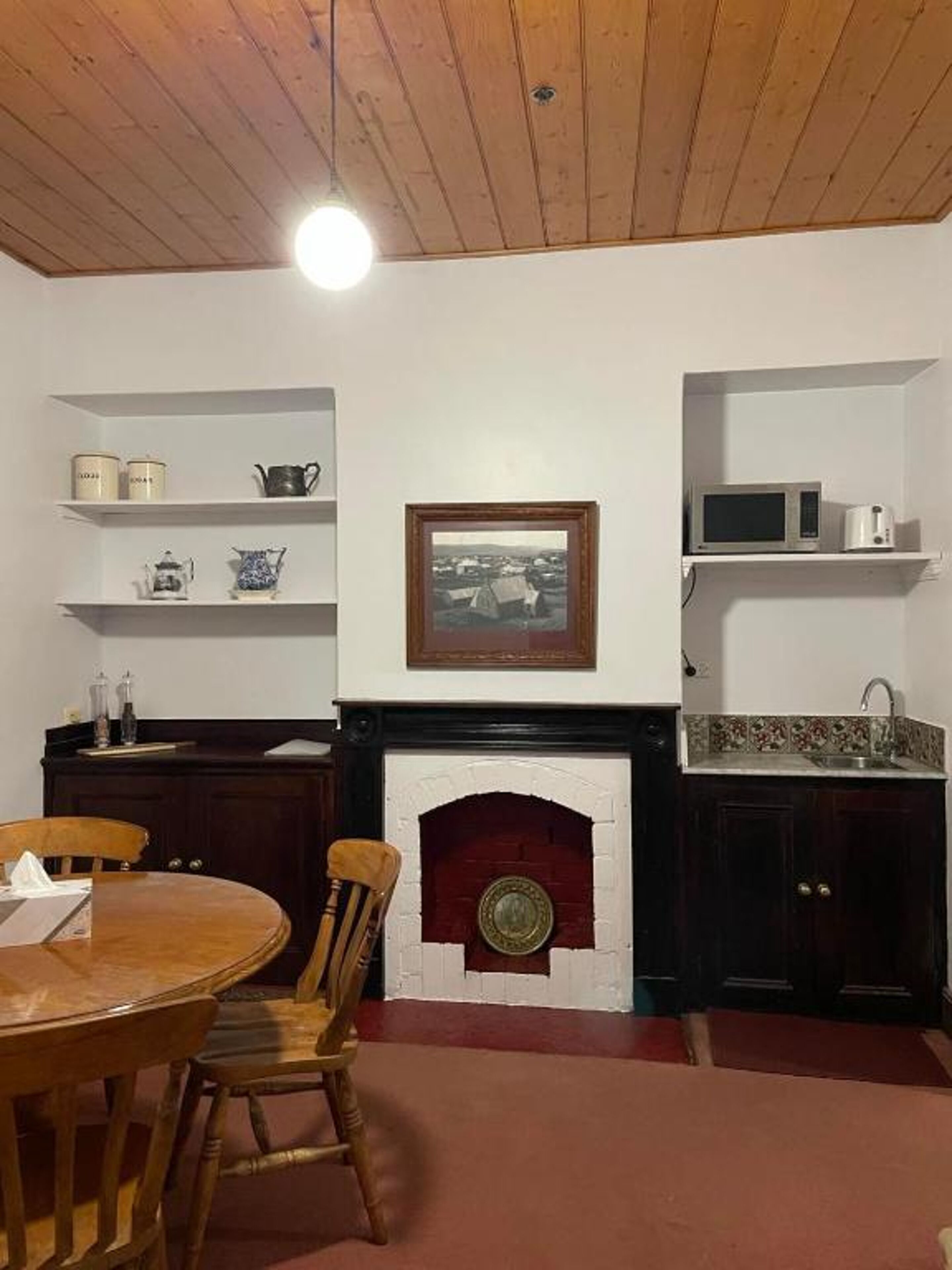 Una cocina con chimenea, armarios de madera y una mesa de comedor con sillas.