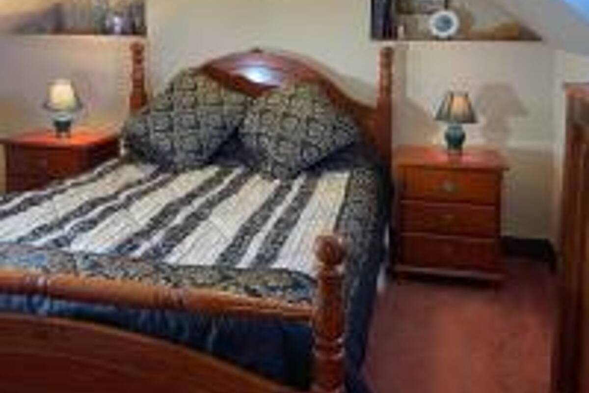 A bedroom with a wooden bed, a nightstand with a lamp, and a dresser.