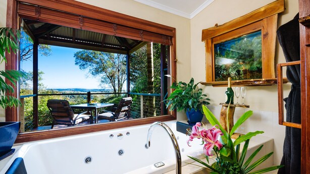 Un baño con una ventana grande, una bañera, un lavabo y un espejo.