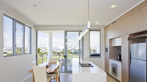 A modern kitchen with a central island, large windows, and a view of the outdoors. - White Shells Luxury Apartments (Marcoola)