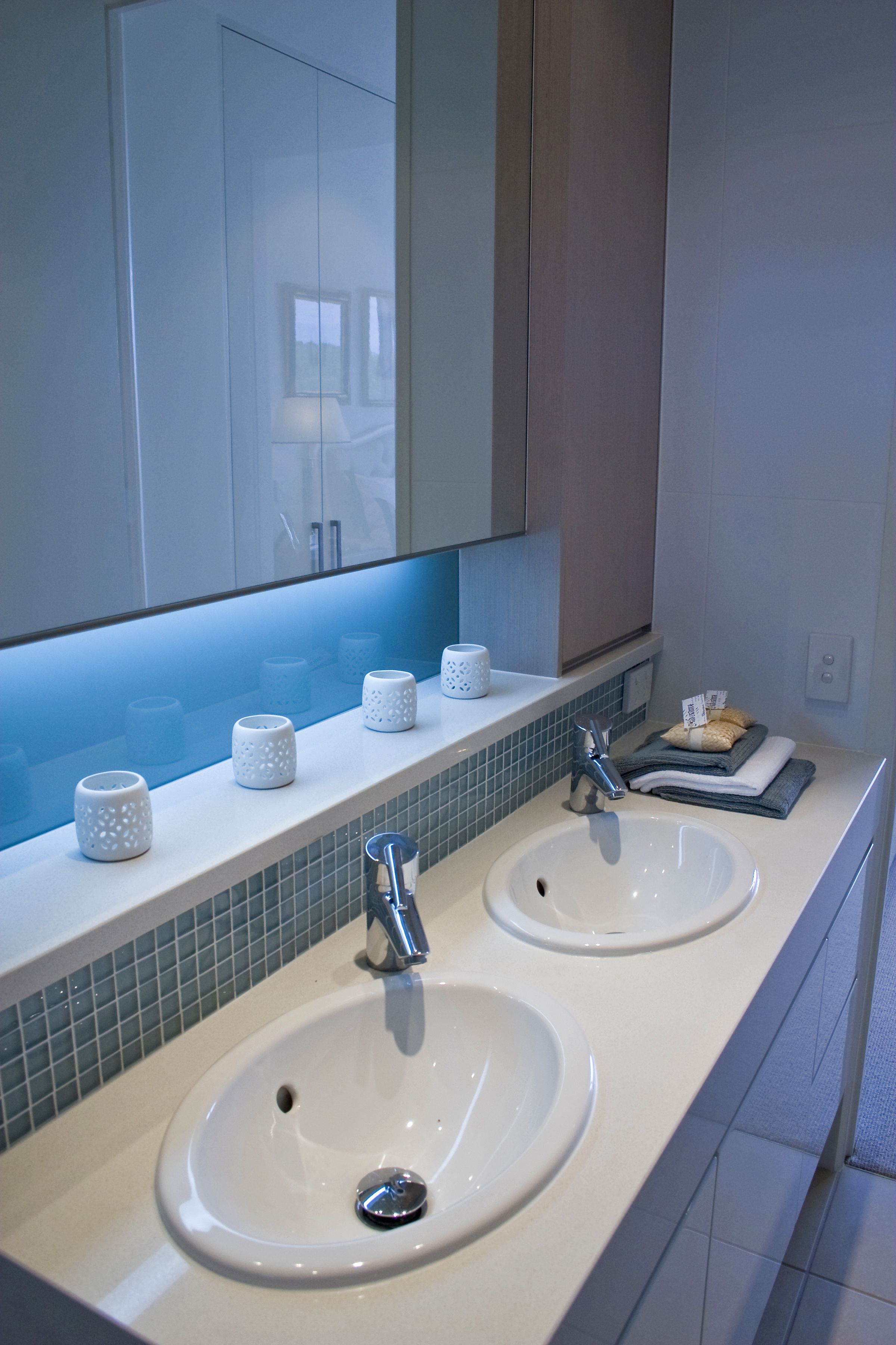 A bathroom with two sinks, a mirror, and a towel rack.