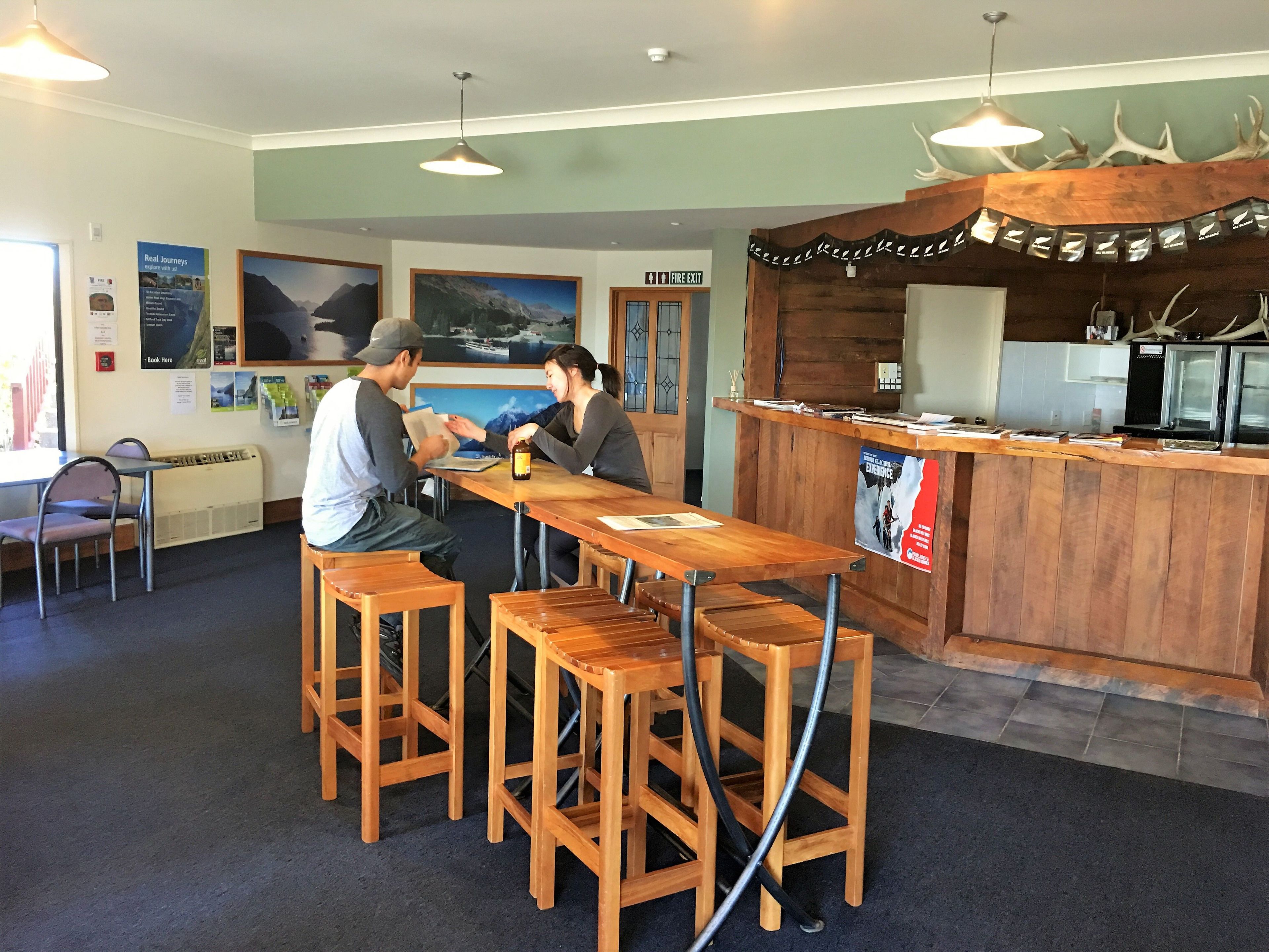 Un ristorante con sgabelli da bar in legno, un bancone con il menu e il segnale di uscita di sicurezza.